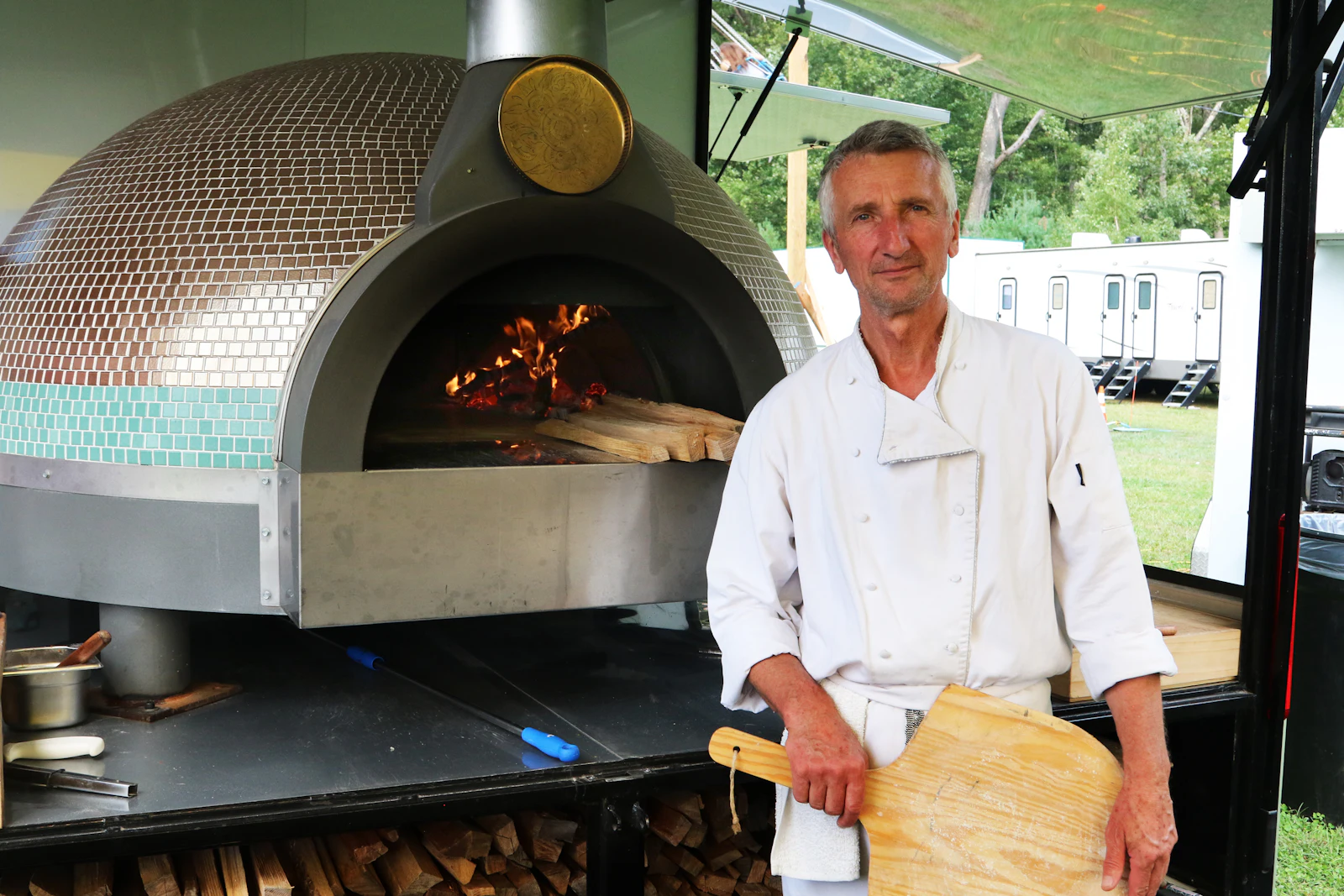 Le chef devant le four avec sa pelle à pizza